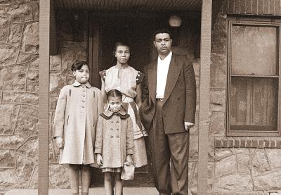 Historical photo of an African American family outside of a house