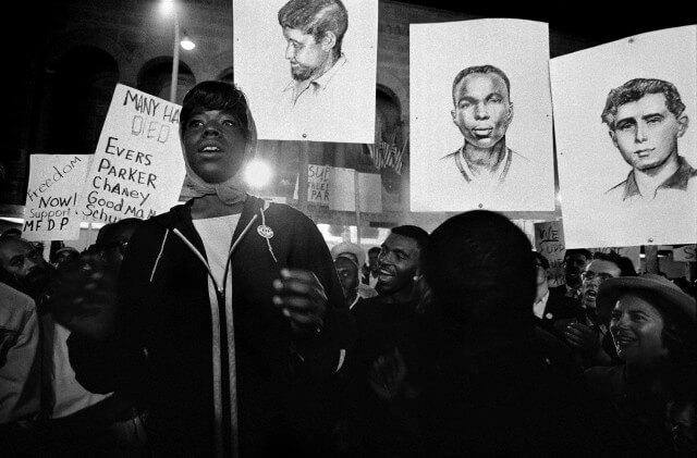 Civil rights activists raise posters with the faces of murdered activists.