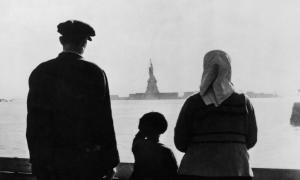 A couple of immigrants with their son look at the Statue of Liberty at distance