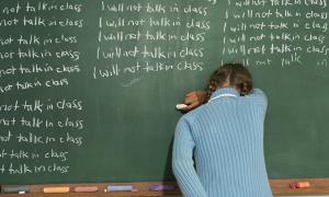Child writing on the chalkboard "I will not talk in class"