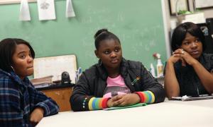 Three black students listen at a table