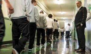 A teacher watches his students pass him in the hallways of a youth correctional facility