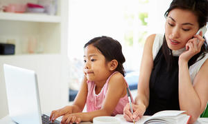 asian mother talking on phone with daughter on computer