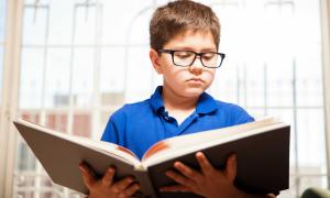 Boy in glasses reading a book