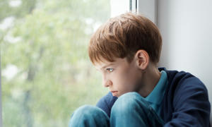 boy sulking staring out window