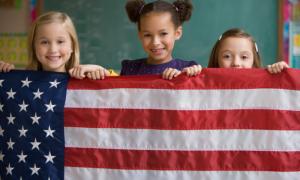 Three kids holding up American flag
