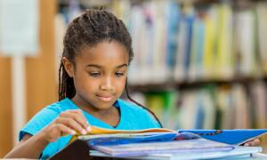 Young African-American girl reading books.