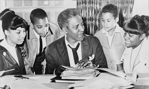 Civil rights and LGBTQ leader Bayard Rustin talking to four students gathered around him.