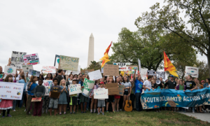 A group of young people holding signs in front of the Washington Monument for the Youth Climate Action Global Climate Strike.