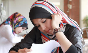 A Muslim girl reads at her desk.