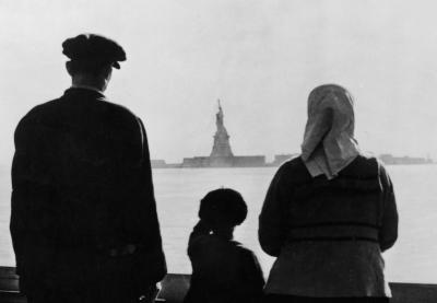 A couple of immigrants with their son look at the Statue of Liberty at distance