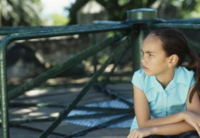 pensive determined youth of color leaning on playground