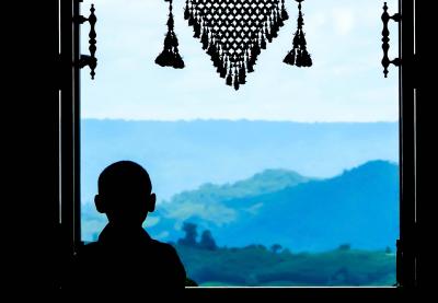 Child looking out onto the countryside, silhouetted in window
