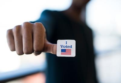 Person with a "I Voted" sticker on their thumb