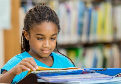 Young African-American girl reading books.