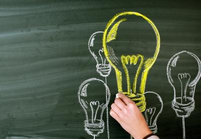 Lightbulbs drawn in yellow and white chalk on a chalkboard.