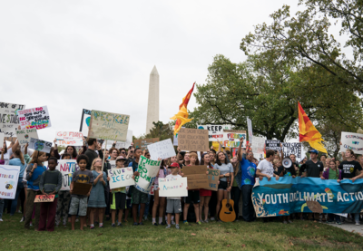 A group of young people holding signs in front of the Washington Monument for the Youth Climate Action Global Climate Strike.