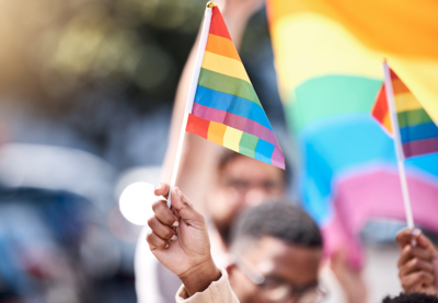 Young Black people carry LGBTQ flags in what looks like a parade. 