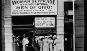 Black and white photo of suffragists in front of their office with signs that read, "Come in and learn why women OUGHT to vote" and "Woman suffrage headquarters. Men of Ohio! Give the women a square deal. Vote for amendment No. 23 on September 3, 1912."