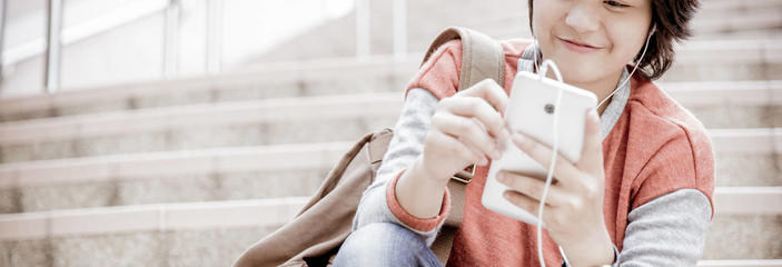 student on steps looking at cell phone smiling