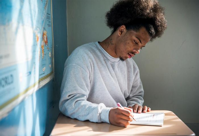 A black student works on an assignment at his desk