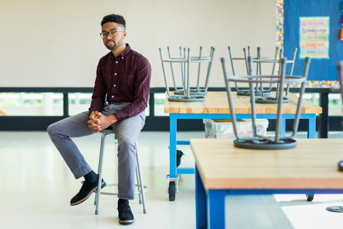Educator Patrick Harris sitting on a stool in a classroom