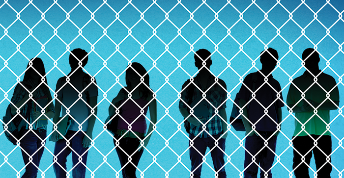 Student silhouettes behind a chainlink fence.
