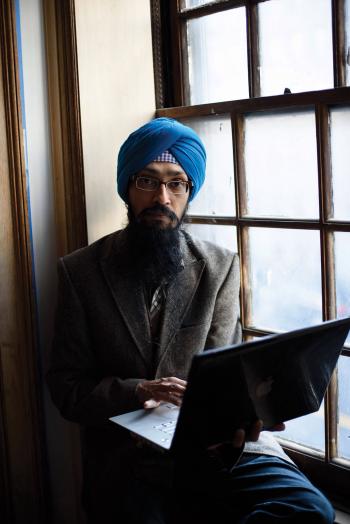Vishavjit Singh sits at a window with his computer.