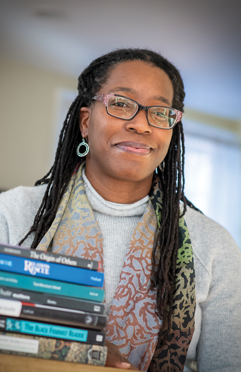 Professor Tiya Miles sitting behind a stack of several books.