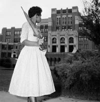 Woman holding a closed umbrella back looking to the front of the Little Rock Central High School