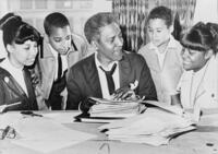 Civil rights and LGBTQ leader Bayard Rustin talking to four students gathered around him.